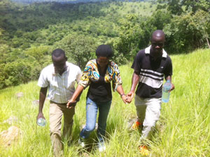 Sam and William give Angella a hand up the mountain in Bugondo.